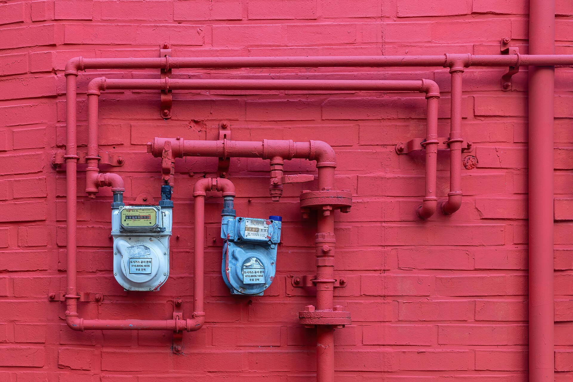 File:Two blue water meters on a matte red painted brick facade with pipes in Seoul.jpg